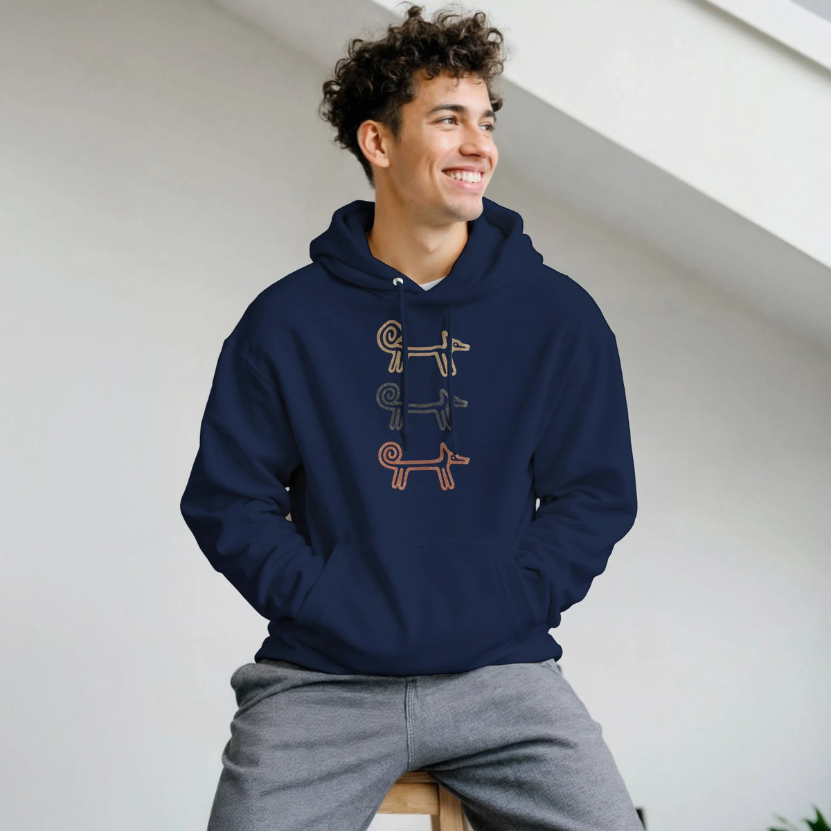 Smiling man seated in the navy Dog Totem men's hoodie