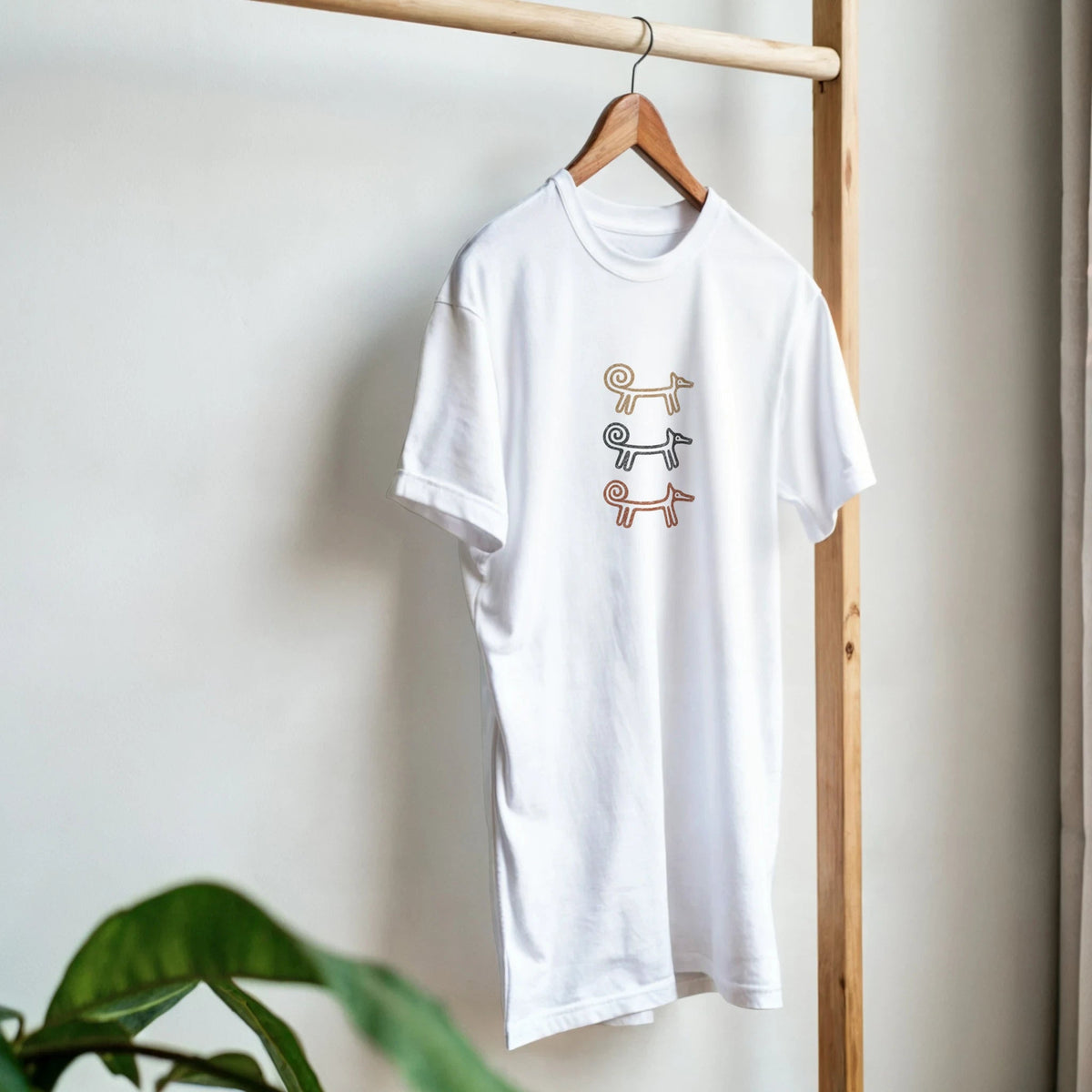 White Dog Totem men's T-shirt on a hanger beside a plant