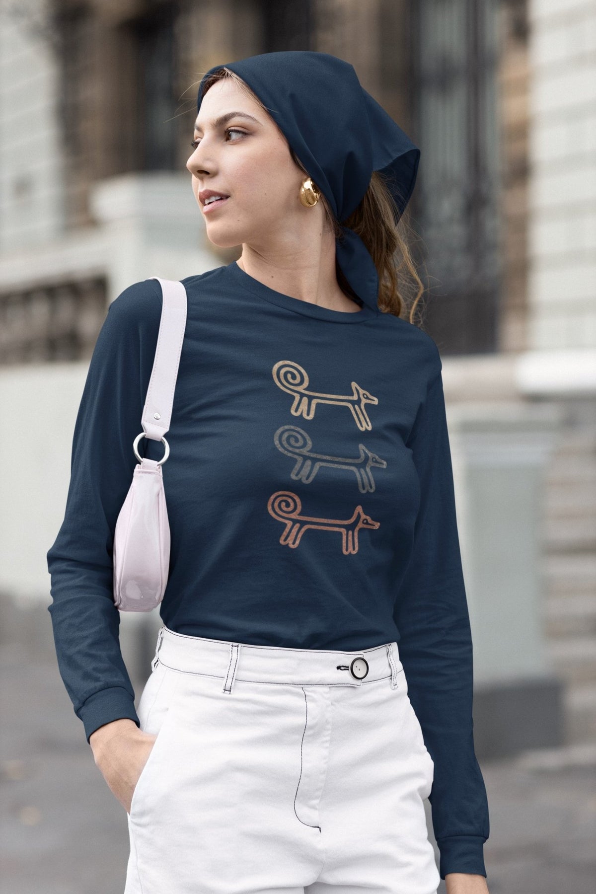 Woman in a headscarf and white trousers wearing the navy Dog Totem long sleeve top