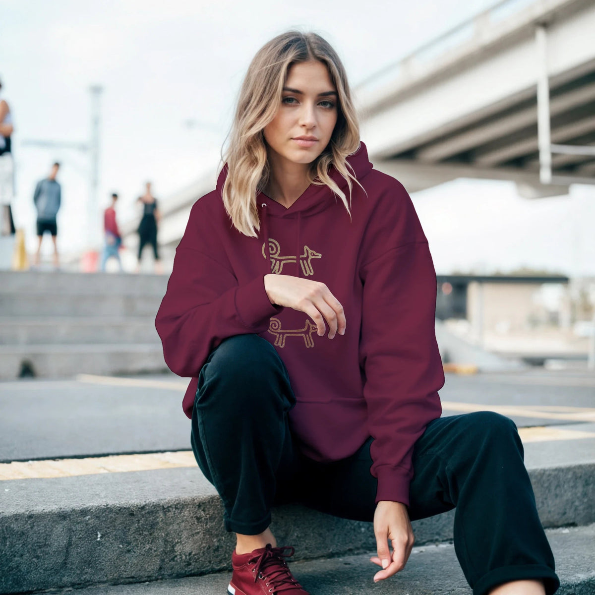 Woman sitting on city steps in the maroon Dog Totem hoodie