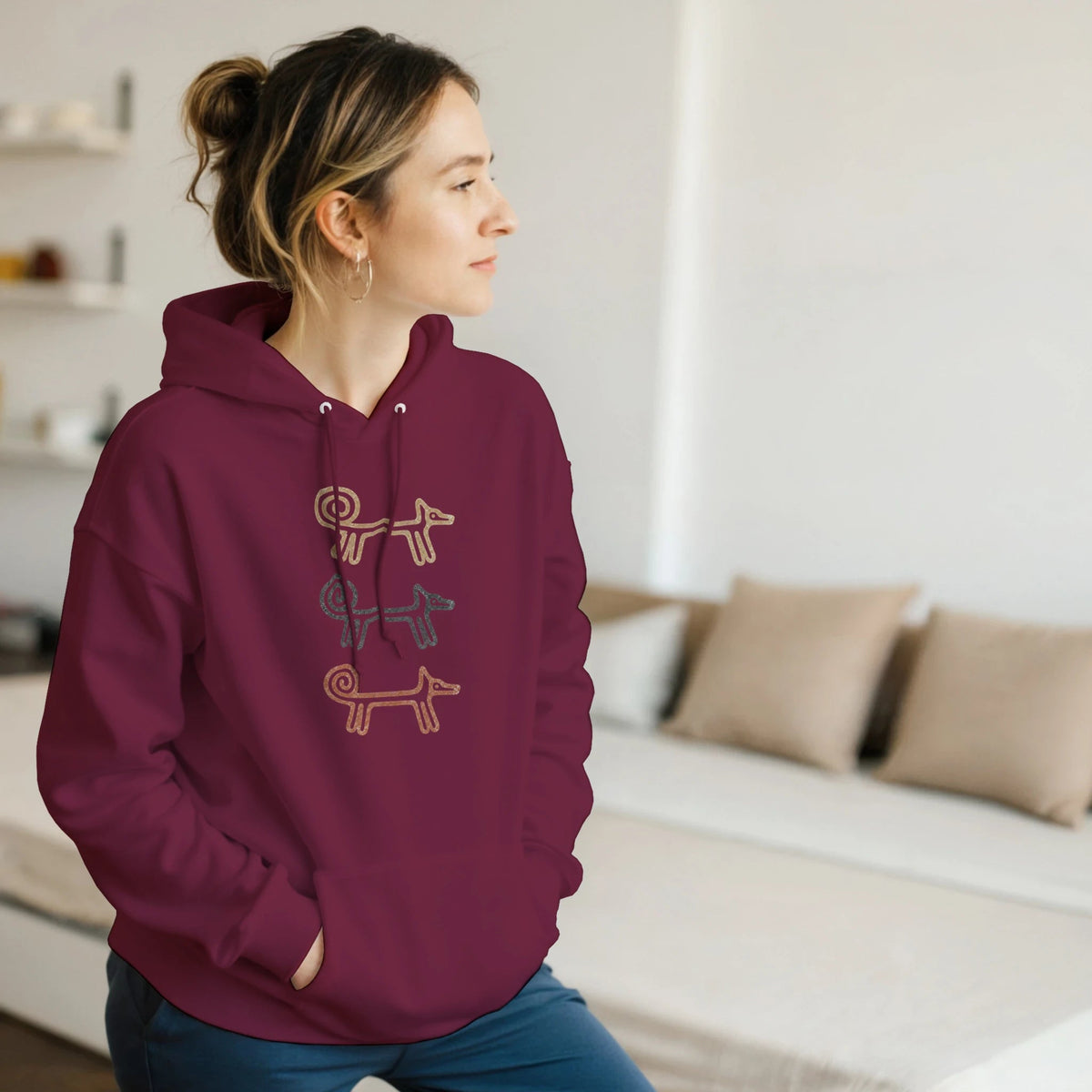 Woman relaxing on a sofa in the maroon Dog Totem women's hoodie